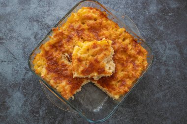 Eritilmiş mozzarella peyniri ile kaplı makarna güveç sosu ve bir masada beyaz bir fırın kabında servis edilir (Türk adı; firinda makarna veya firin makarna)