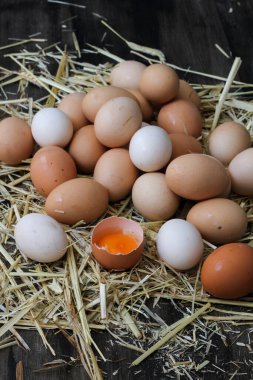 Stack of egg on straw with wooden table background.Top view.
