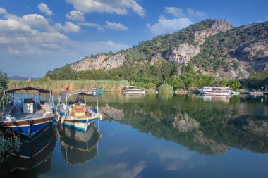 Türkiye 'nin Mugla ilinin Dalyan kentindeki Kaunos antik kentinin kaya kesimli tapınak mezarları. Arka planda kamış yatakları, tekne gezisi ve oyulmuş mezarları olan Dalyan nehrinin güzel manzarası..
