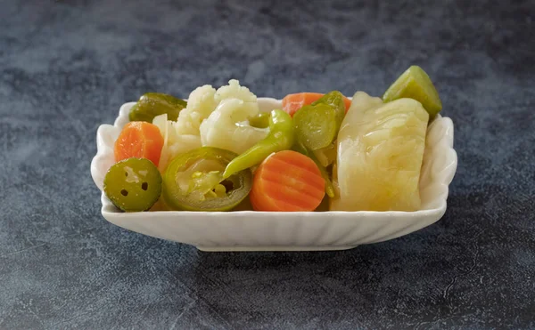 Turkish mixed pickles (Carrot, pepper, tomato, cauliflower, cabbage, garlic) in a white plate