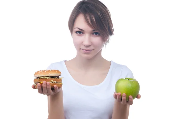 Menina faz escolha entre maçã e hambúrguer — Fotografia de Stock