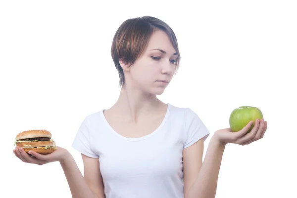 Girl makes choice between apple and hamburger — Stock Photo, Image