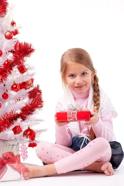 Mädchen sitzt auf dem Boden neben einem weißen künstlichen Weihnachtsbaum mit Geschenken — Stockfoto