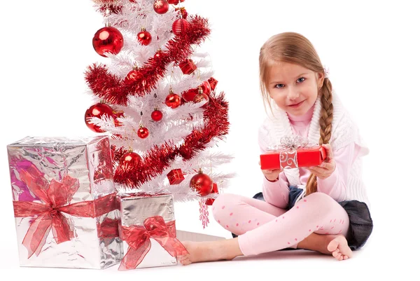 Girl sitting on the floor near a white artificial Christmas tree with gifts — Stok fotoğraf