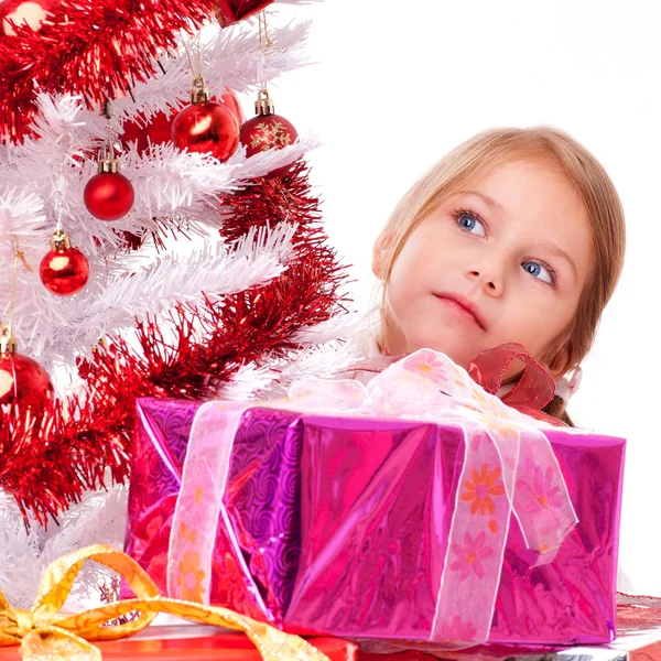 Chica reflexiva con regalos de Navidad cerca de un árbol de Navidad artificial blanco — Foto de Stock