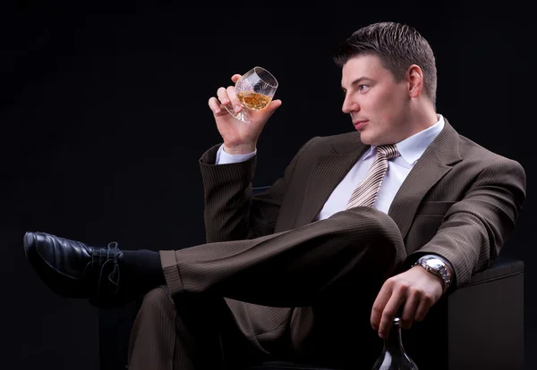 Joven empresario sentado en un sofá con una bebida alcohólica —  Fotos de Stock