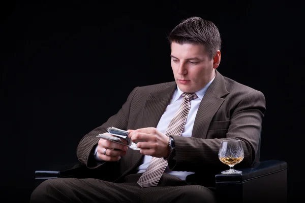 Young businessman with money and an alcoholic beverage sitting in the chair — Stock Photo, Image