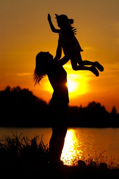 Mother and daughter against summer sunset — Stock Photo, Image