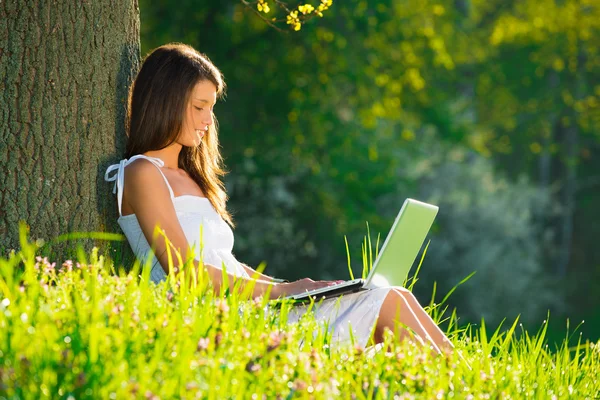 Mulher bonita relaxante na grama com laptop — Fotografia de Stock