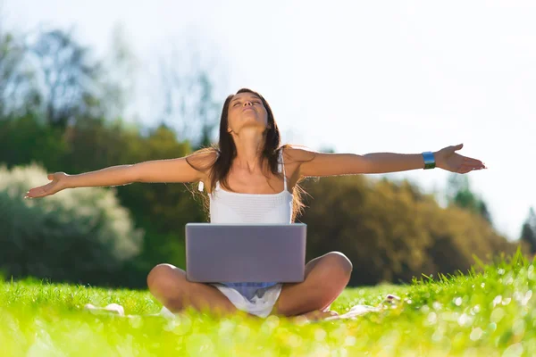 Retrato de uma jovem excitada desfrutando de sucesso ao usar um laptop na grama — Fotografia de Stock