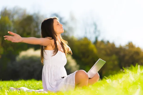 Retrato de una joven y feliz usando una laptop sentada en un parque —  Fotos de Stock