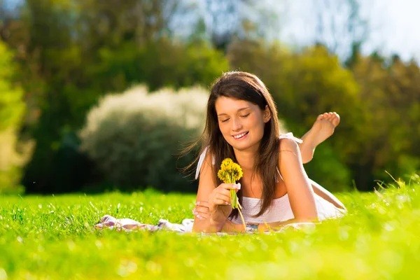 Souriante jeune femme tenant des fleurs joyeusement — Photo