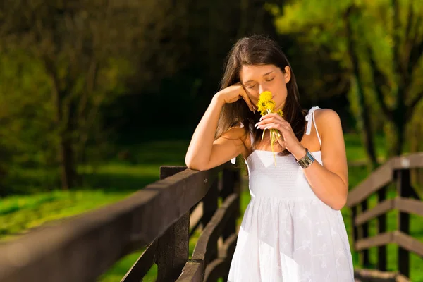 Souriante jeune femme tenant des fleurs joyeusement — Photo