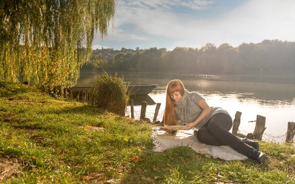 Mulher lendo junto ao lago — Fotografia de Stock