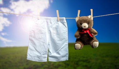 Bebek bir pantolon, bir oyuncak ayı açık clothesline üzerinde