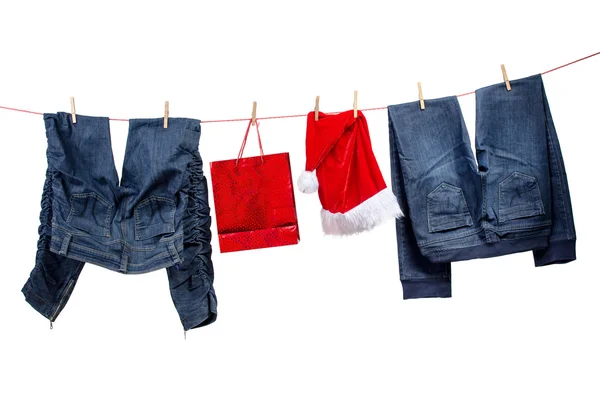 Jeans com saco de presente e chapéus de Papai Noel no varal — Fotografia de Stock