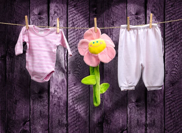 Roupas de menina e uma flor em um varal — Fotografia de Stock