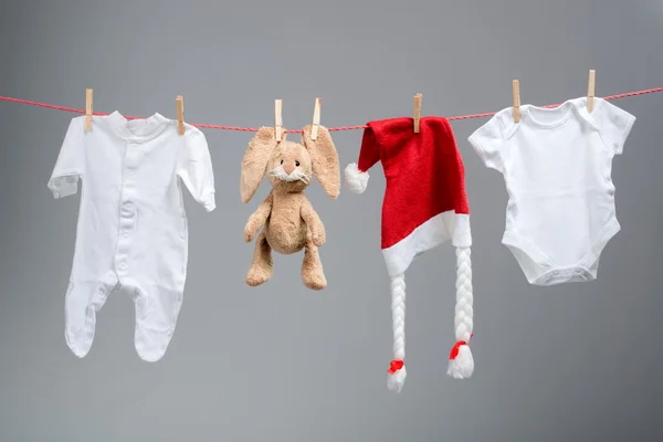 Bir clothesline bebek giysileri ve santa şapka — Stok fotoğraf