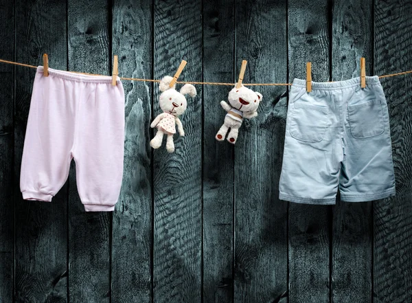 Baby clothes and a teddy bear on clothesline — Stock Photo, Image