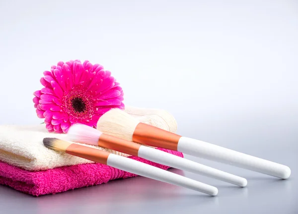 Cepillos para maquillaje en toalla con flor rosa grande —  Fotos de Stock