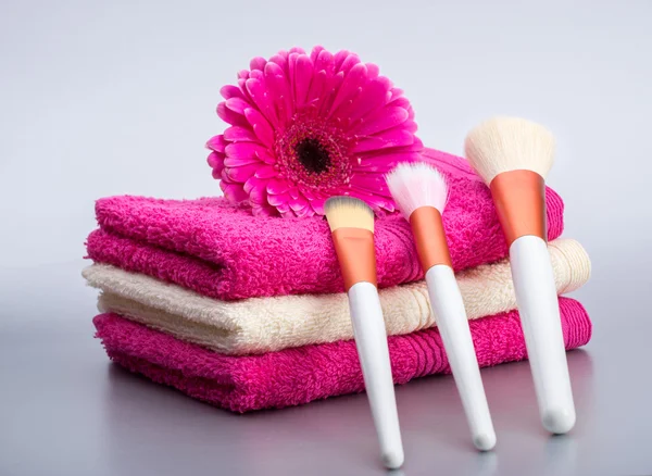 Cepillos para maquillaje en toalla con flor rosa grande — Foto de Stock