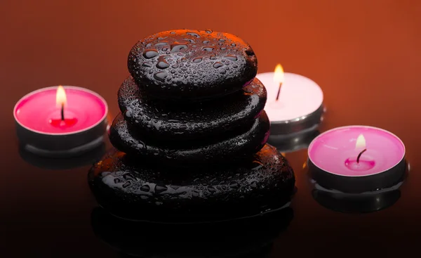 Piedras de masaje con velas encendidas y gotas de agua — Foto de Stock