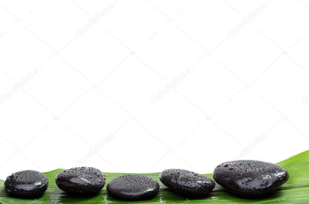 Spa stones on green leaf, isolated background