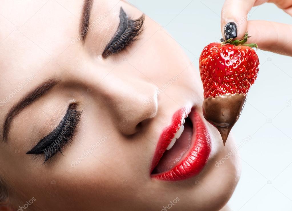 Red female lips eating chocolate strawberries