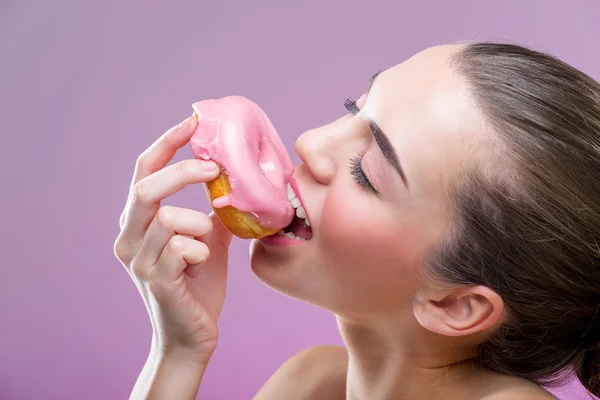 Güzel, seksi bir kadın, bir donut yemek — Stok fotoğraf