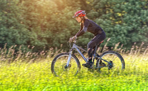 スポーツ バイク女性は美しい牧草地で — ストック写真