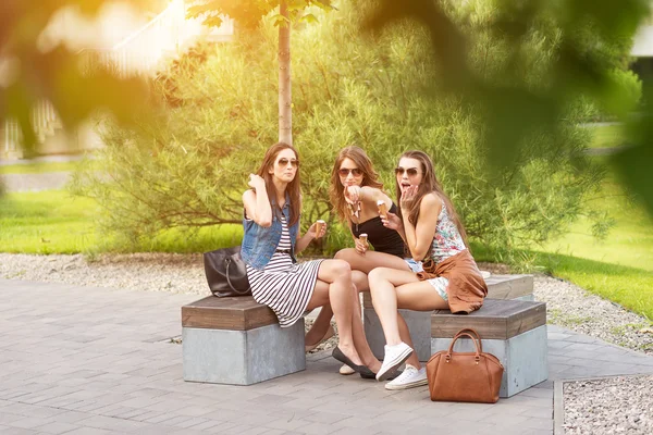 Três belas namoradas comem sorvete, posando sob a árvore — Fotografia de Stock