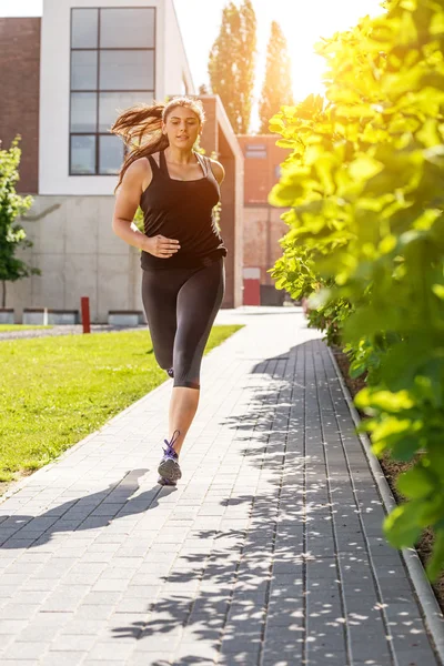 Mujer corriendo en traje deportivo negro en la acera —  Fotos de Stock