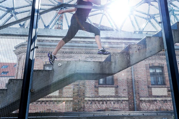 Kör kvinna i svart sport outfit, kör upp för trapporna — Stockfoto