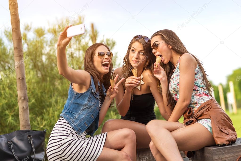 Three beautiful girlfriends eating ice cream while Selfie photo