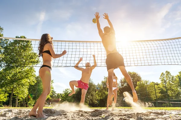 Друзья играют в волейбол на пляже — стоковое фото