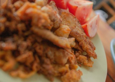 Kendi yemeğini kendin yap. Yumurta karışımı ve un karışımı, etin üzerine kaplanmış ve yağla kızartılıyor; tabakta domatesler var; ve yanında pırasa olan kızarmış domuz eti var..