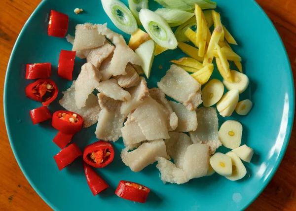 In the blue plate, there is hot water blanched pork, sliced garlic and green onion, and julienned ginger; in red are red chili peppers cut into small pieces, which look very spicy.