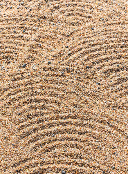 Closeup on a texture background of gravels in a Japanese zen dry  garden made by priest with a rake depicting patterns recalling waves or rippling water known as samon or hokime in Hama-rikyu Gardens.
