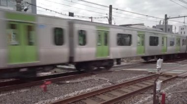 Tokyo, Japonya - 25 Kasım 2021: Komagome 'da bulunan Nakazato demiryolu geçidi 2 adlı düzlem üzerinde Yamanote demiryolu hattından geçen bir E235 seri treninin Pan videosu.