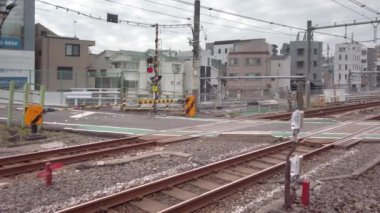 Tokyo, Japonya - 25 Kasım 2021: Komagome 'da bulunan Nakazato Demiryolu Geçidi II adlı düzlemden geçen bir E235 serisi treniyle Yamanote hattının tren yolunun Pan videosu.
