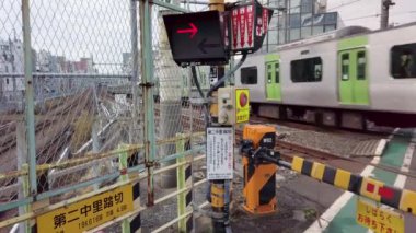 Tokyo, Japonya - 25 Kasım 2021: Nakazato Demiryolu Geçidi II adlı Yamanote hattının son katındaki Japon demiryolu trenine yaklaşırken sinyal ışıklarının yanıp söndüğü videoyu kaldır.