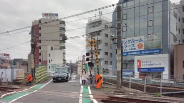 Tokyo, Japonya - 25 Kasım 2021: Komagome ve Tabata arasında Nakazato demiryolu geçidi adı verilen Yamanote hattının son seviyesinde maske takan bir Japon taksi arabasının videosu.
