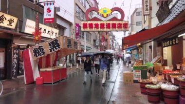 Tokyo, Japonya - 14 Ekim 2019: Sugamo Jizo alışveriş sokağında Japonların yağmurda şemsiyelerle yürüdükleri gösterişli bir kapı ve Muscovado esmer şeker satan bir pazar yeri videosu.