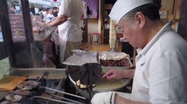Tokyo, Japonya - 28 Ocak 2019: Asakusa 'nın Nakamise alışveriş caddesinde pişmiş oyuncak bebek anlamına gelen ningyo-yaki adı verilen kırmızı fasulye kreması pişiren Japon bir zanaatkârın videosu.
