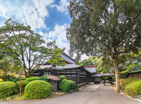 kyushu, japan - december 08 2021: Exterior corridor in the back of the Miyajidake Shrine of Fukuoka passing through its backyard adorned with rounded niwaki shrubs and a big Nozura stone lantern.