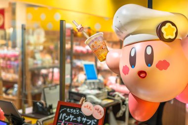 tokyo, japan - sept 21 2022: Kirby figurine, the Nintendo games pink ball character wearing a toque hat like a chef and holding a bubble tea cup at the Kirby Cafe of Soramachi mall in Tokyo Skytree. clipart