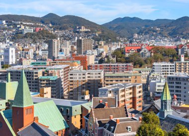 Nagasaki, kyushu - 13 Aralık 2021: Oura Katolik Kilisesi 'nin çan kulesi ve Hiko san Dağı' nın eteklerindeki Glover Bahçesi 'nden kuş bakışı manzara.
