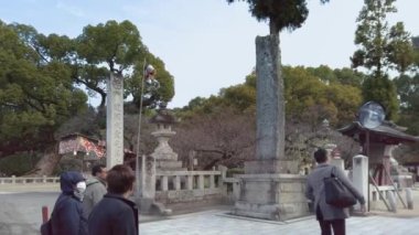 Kyushu, Japonya - Aralık 07 2019: Japon Dazaifu türbesini gezmek için Torii portallarına doğru rehberlerinin arkasında yürüyen Çinli bir turist grubunun videoları.