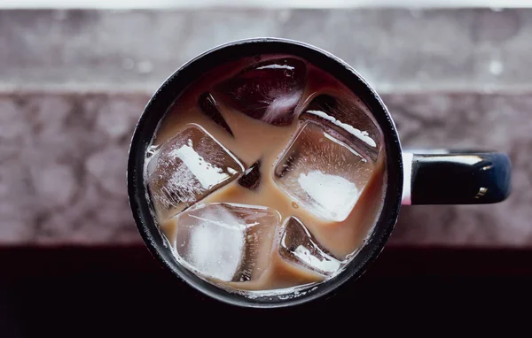 Eski ahşabın üstünde buzlu bir fincan kahve.