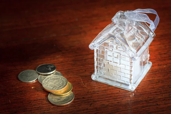 Kleines Haus und Münzen auf Holz Hintergrund Textur — Stockfoto